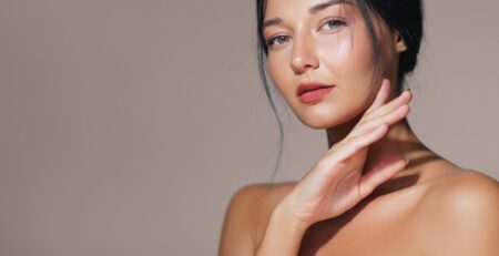 A woman examining smooth, refreshed skin in a mirror at a med spa in Jericho, Long Island, after a Botox treatment